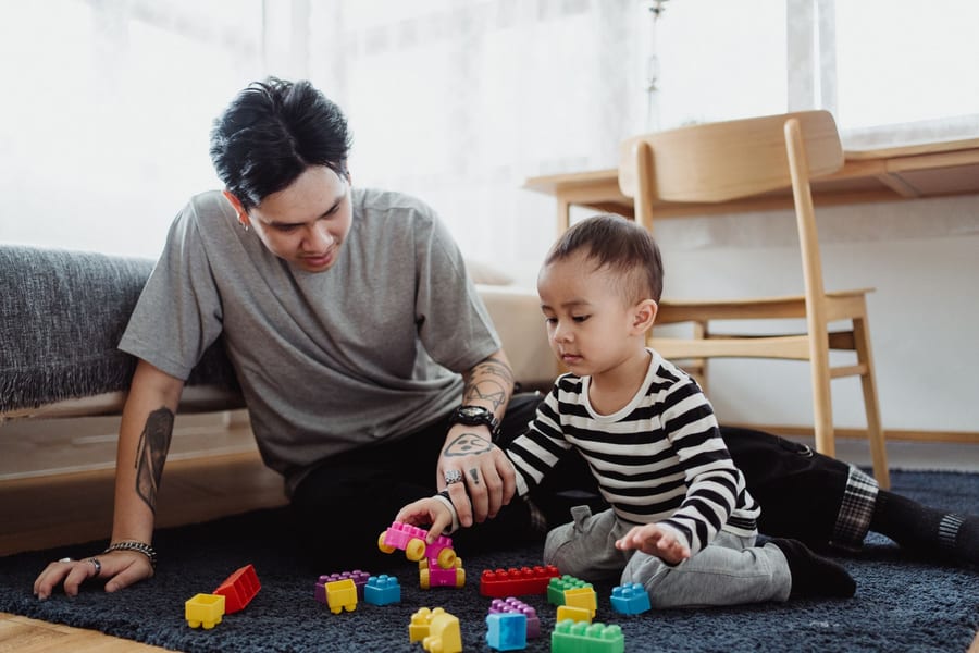 A father and young son building with blocks on the floor at home
