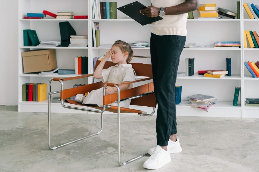 A child in a session with a clinician holding a clipboard